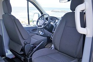 the interior of a van with seats and a view of the ocean.