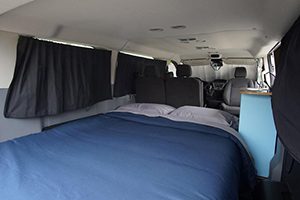the interior of a van with a bed and curtains.