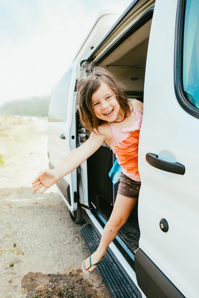 a little girl is getting out of a van.