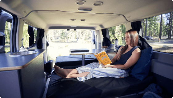 a woman in a van reading a book.
